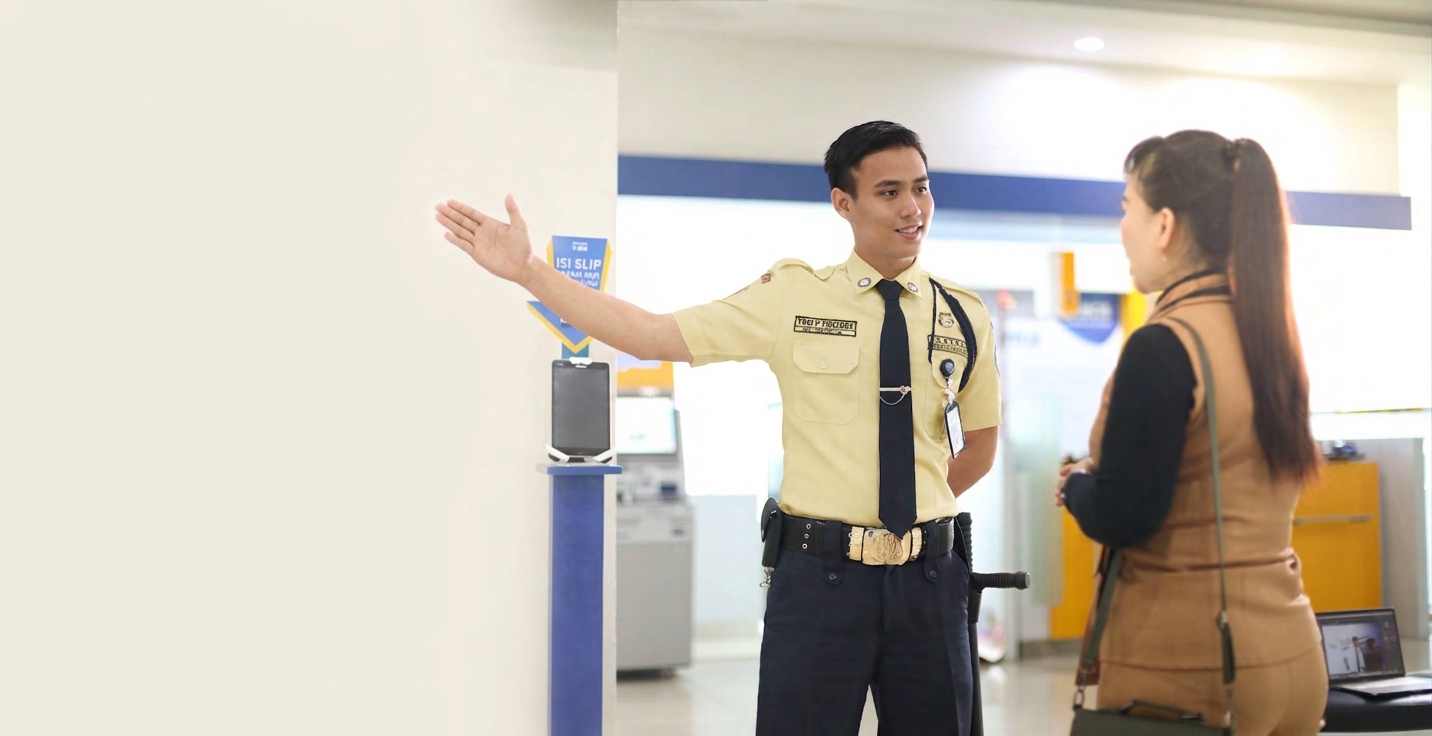 Satpam mengarahkan pengunjung di area lobi